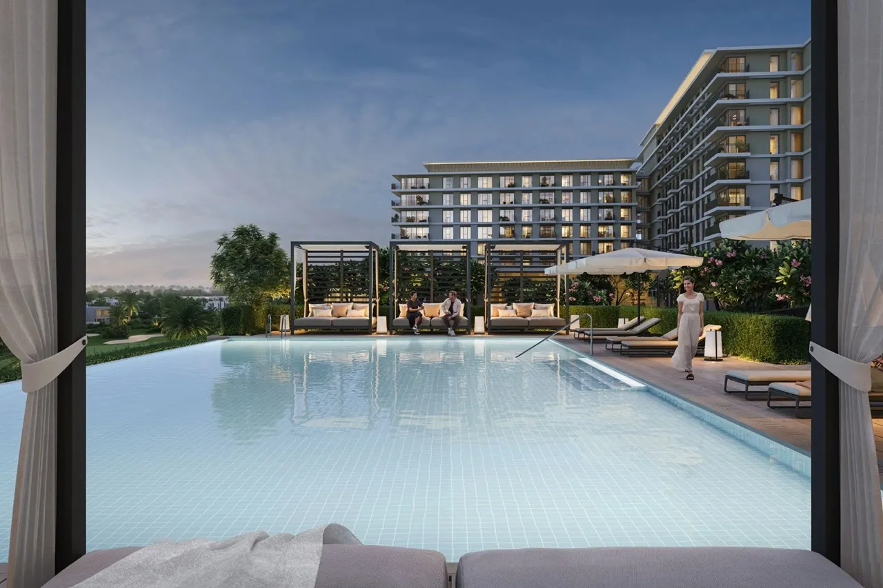 Golf Hills at Emaar South by Emaar infinity pool with lounge seating cabanas and residential buildings at sunset in Dubai - Presented by Tohid Fetrat