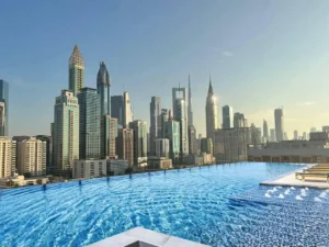 Grandala at Jumeirah Garden City by Palladium Developments rooftop infinity pool overlooking Dubai skyline with modern towers and city view - Presented by Tohid Fetrat