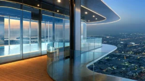 LUMENA by Omniyat office tower sky pool and curved balcony with glass railing overlooking Dubai cityscape at night - Presented by Tohid Fetrat
