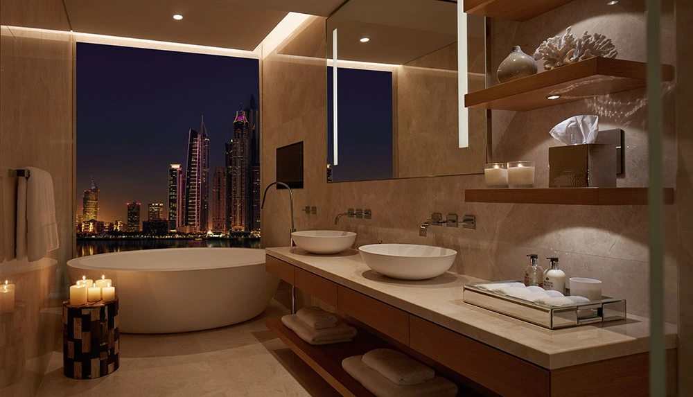 One at Palm Jumeirah Dorchester Collection by Omniyat bathroom with freestanding bathtub and night skyline view in Dubai - Presented by Tohid Fetrat