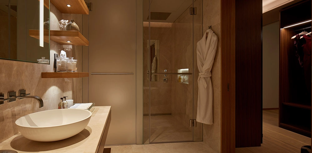 One at Palm Jumeirah Dorchester Collection by Omniyat bathroom with modern vanity sink glass shower and warm lighting in Dubai - Presented by Tohid Fetrat