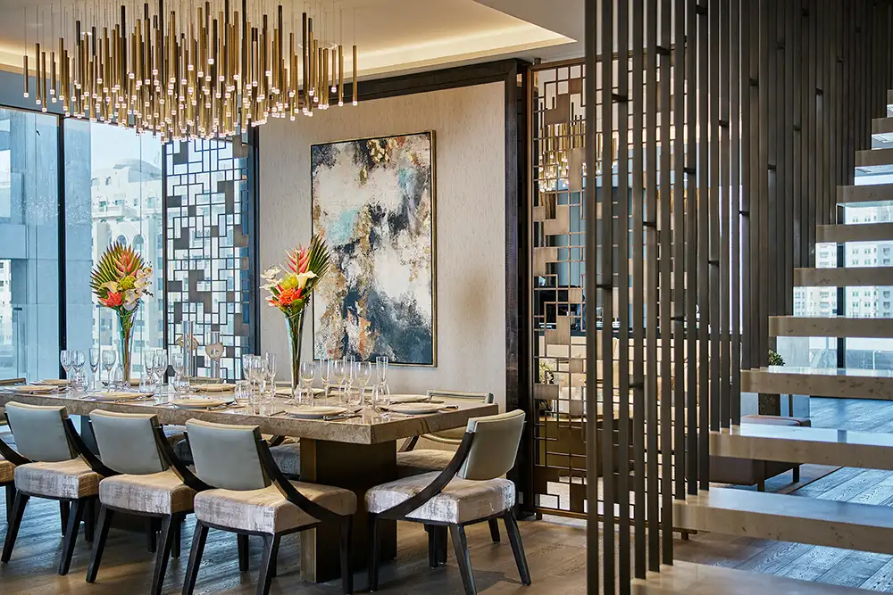 One at Palm Jumeirah Dorchester Collection by Omniyat dining area with statement chandelier and staircase detail in Dubai - Presented by Tohid Fetrat