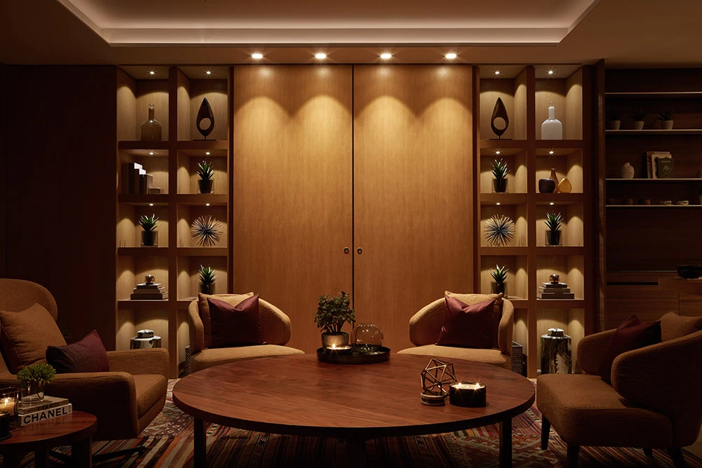 One at Palm Jumeirah Dorchester Collection by Omniyat lounge with wood shelving decorative objects and warm lighting in Dubai - Presented by Tohid Fetrat