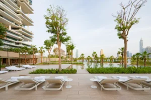 One at Palm Jumeirah Dorchester Collection by Omniyat poolside lounge deck with sunbeds and landscaped views in Dubai - Presented by Tohid Fetrat