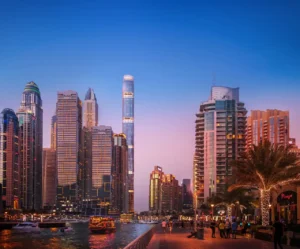 Six Senses Residences Dubai Marina by Select Group view of Dubai Marina Walk at night with illuminated skyline waterfront promenade and boats in Dubai - Presented by Tohid Fetrat