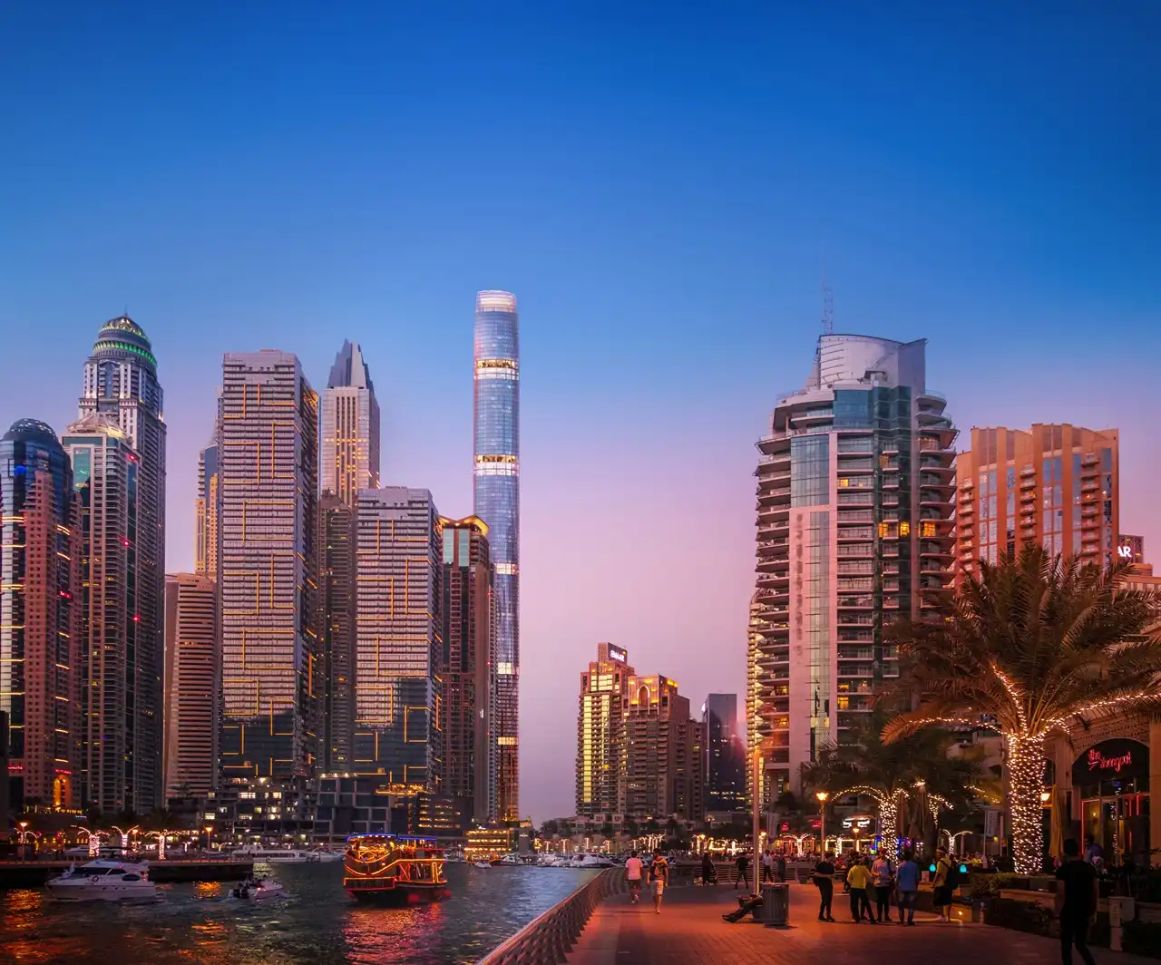 Six Senses Residences Dubai Marina by Select Group view of Dubai Marina Walk at night with illuminated skyline waterfront promenade and boats in Dubai - Presented by Tohid Fetrat