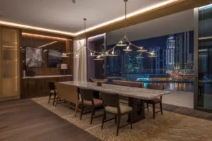 The Lana Residences Dorchester Collection by Omniyat 4 bedroom dining area with city night view and modern chandelier lighting in Dubai - Presented by Tohid Fetrat