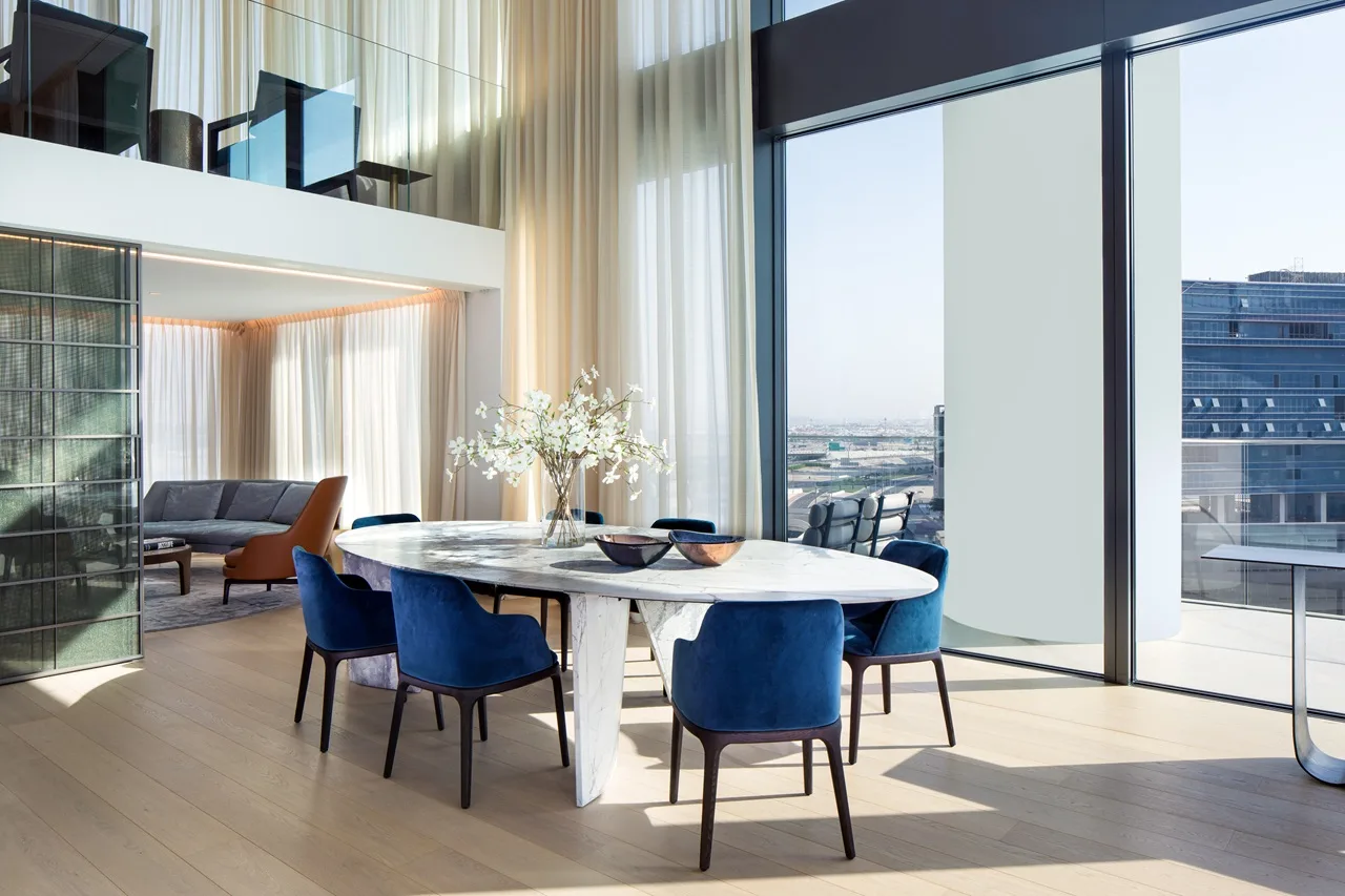 The Lana Residences Dorchester Collection by Omniyat 4 bedroom duplex dining area with marble table blue chairs and floor to ceiling windows in Dubai - Presented by Tohid Fetrat