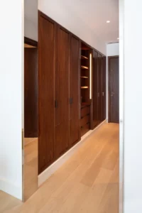 The Lana Residences Dorchester Collection by Omniyat 4 bedroom duplex walk in wardrobe corridor with custom wood cabinetry and integrated lighting in Dubai - Presented by Tohid Fetrat