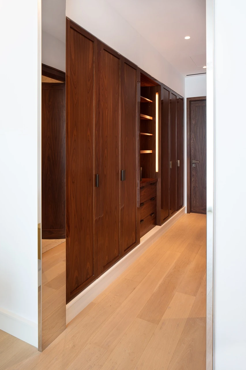 The Lana Residences Dorchester Collection by Omniyat 4 bedroom duplex walk in wardrobe corridor with custom wood cabinetry and integrated lighting in Dubai - Presented by Tohid Fetrat