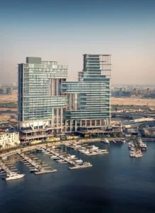 The Lana Residences Dorchester Collection by Omniyat aerial view of waterfront towers and marina with yachts in Dubai - Presented by Tohid Fetrat