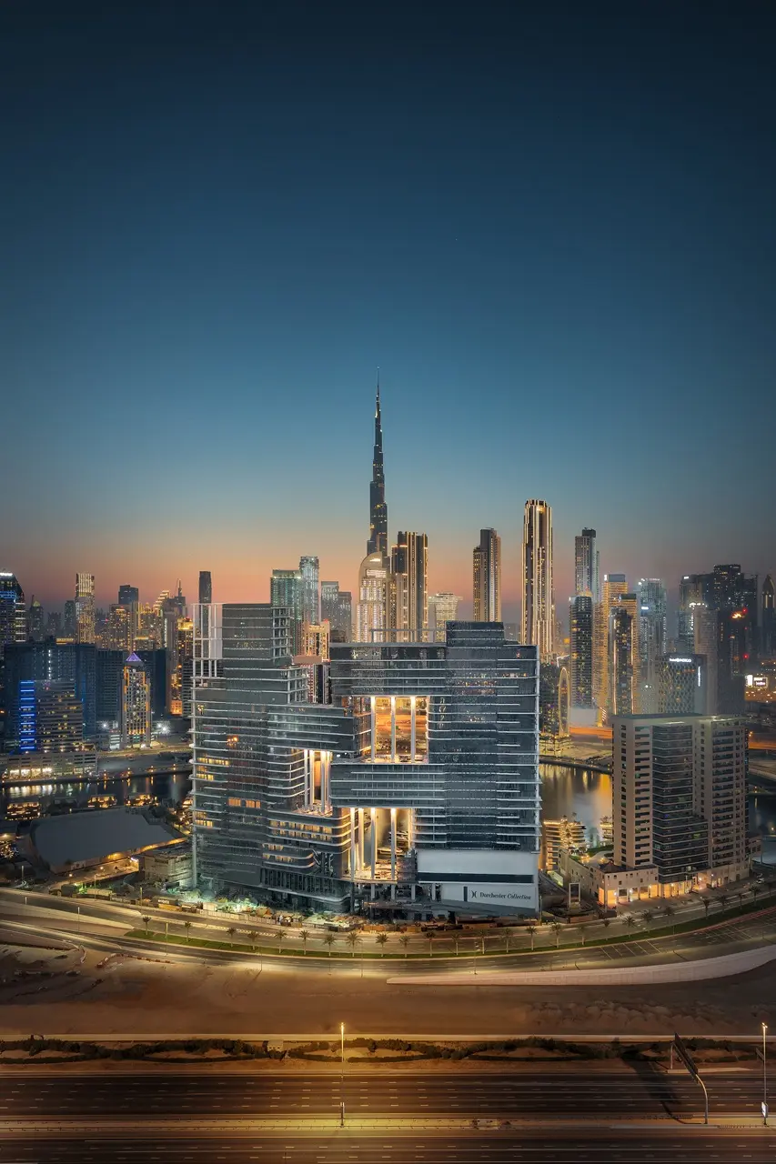 The Lana Residences Dorchester Collection by Omniyat illuminated towers with Downtown Dubai skyline and Burj Khalifa at night in Dubai - Presented by Tohid Fetrat