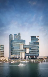 The Lana Residences Dorchester Collection by Omniyat waterfront towers with marina and yachts under clear blue sky in Dubai - Presented by Tohid Fetrat