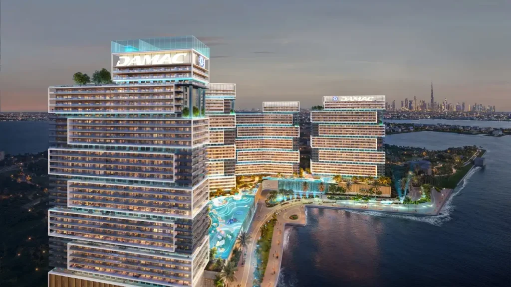 Chelsea Residences by DAMAC construction update showing waterfront development with illuminated buildings and lagoon style amenities in Dubai Presented by Tohid Fetrat