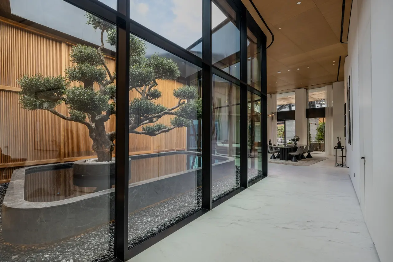 The Opus Penthouse by OMNIYAT entrance corridor with indoor courtyard, sculptural tree feature, and contemporary architectural design in Dubai - Presented by Tohid Fetrat