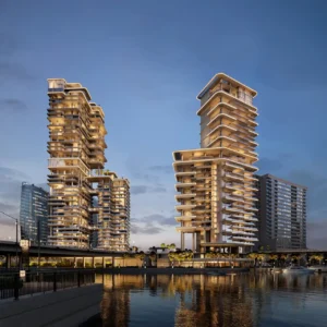 VELA and Vela Viento by Omniyat illuminated waterfront residential towers at night along Dubai Water Canal in Dubai - Presented by Tohid Fetrat
