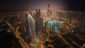 Binghatti Skyblade by Binghatti illuminated residential tower overlooking Downtown Dubai skyline Burj Khalifa and Dubai Fountain at night in Dubai - Presented by Tohid Fetrat