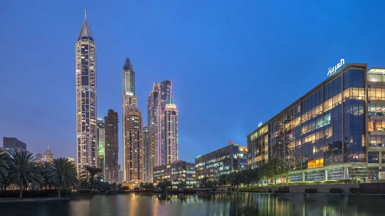 Dubai Media City waterfront skyline with illuminated office buildings and modern skyscrapers at dusk Presented by Tohid Fetrat