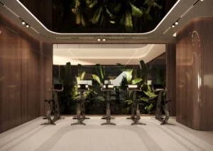 ORLA, Dorchester Collection, Dubai by OMNIYAT cycling studio featuring premium stationary bikes, contemporary fitness interiors, ambient lighting, and landscaped garden views in Dubai. Presented by Tohid Fetrat