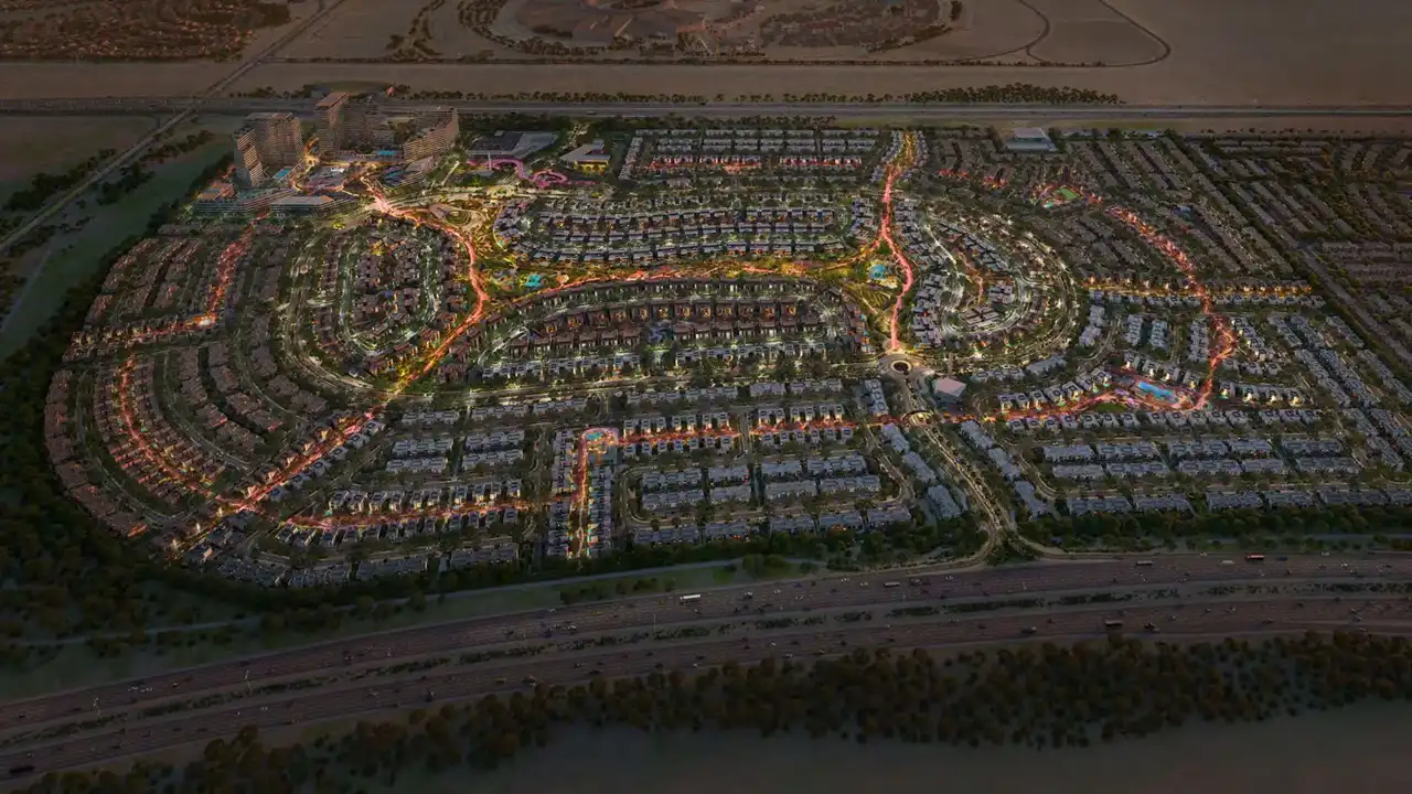 Evening aerial view of the Arabian Ranches 3 masterplan showcasing illuminated residential neighborhoods, landscaped streets, and community amenities in Dubai. Presented by Tohid Fetrat
