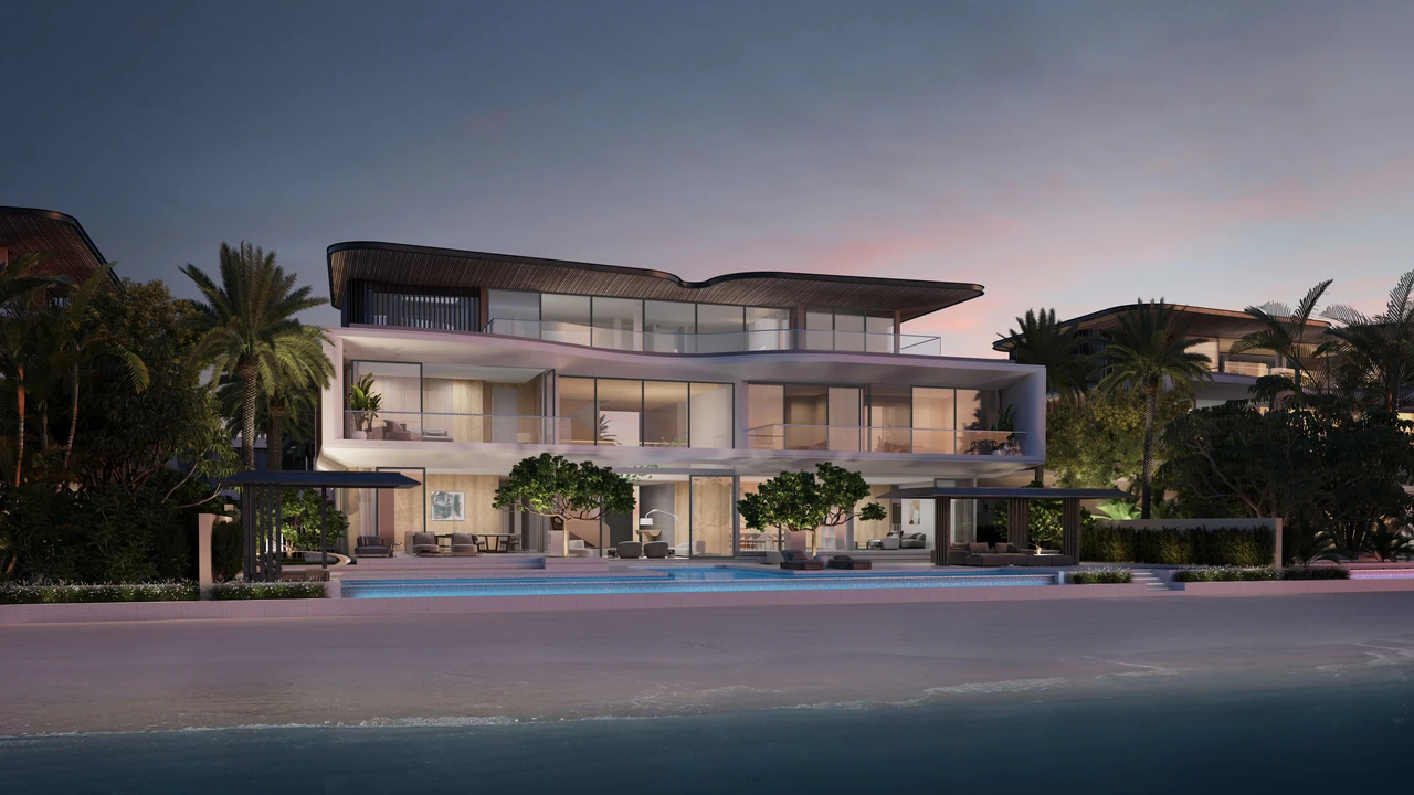 Frond A by Nakheel in Palm Jebel Ali Red Aurora villa exterior at dusk with curved balcony edges lit interiors pool terrace and beach frontage in Dubai - Presented by Tohid Fetrat
