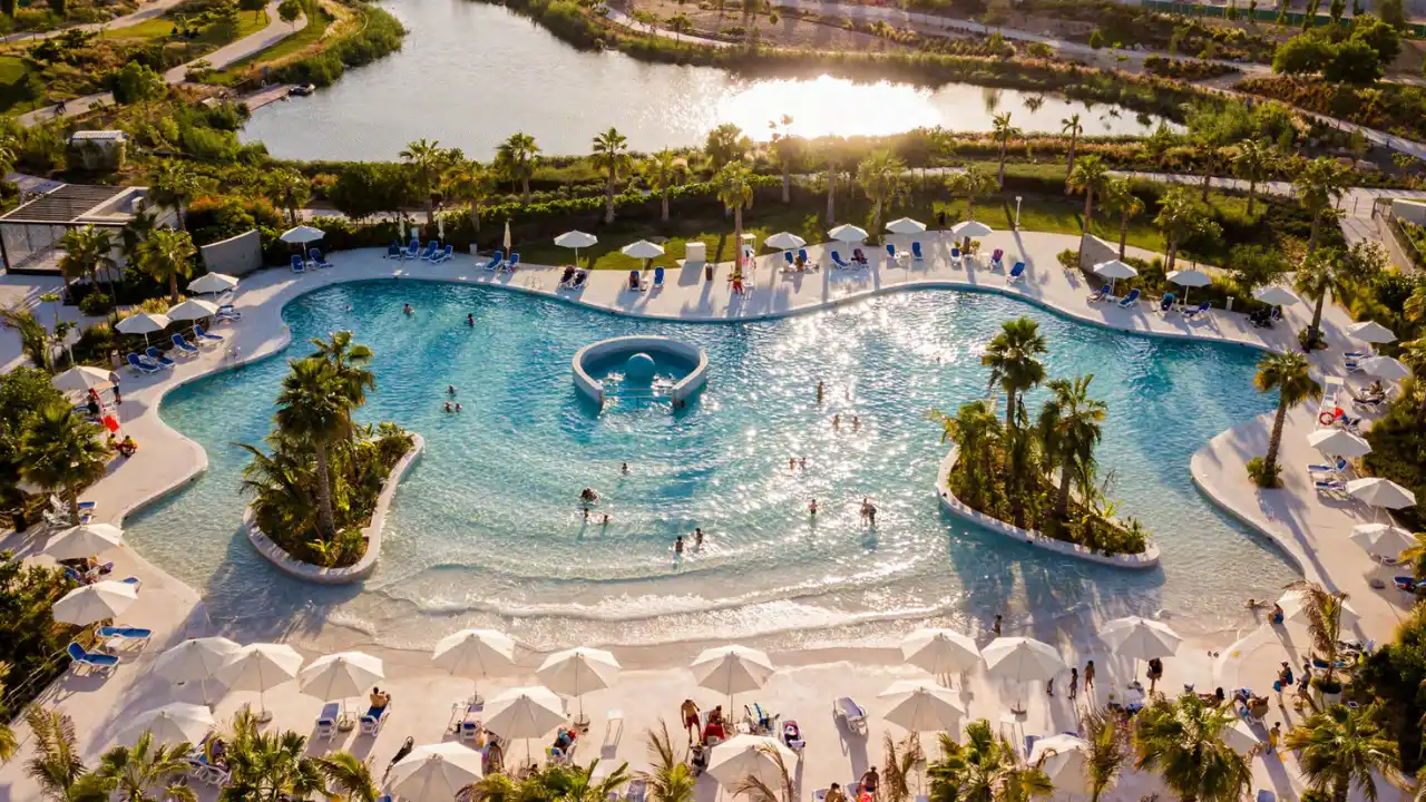 Golf Gate 2 at DAMAC Hills by DAMAC Properties community lagoon style swimming pool with palm trees sun loungers and landscaped waterfront surroundings in Dubai Presented by Tohid Fetrat