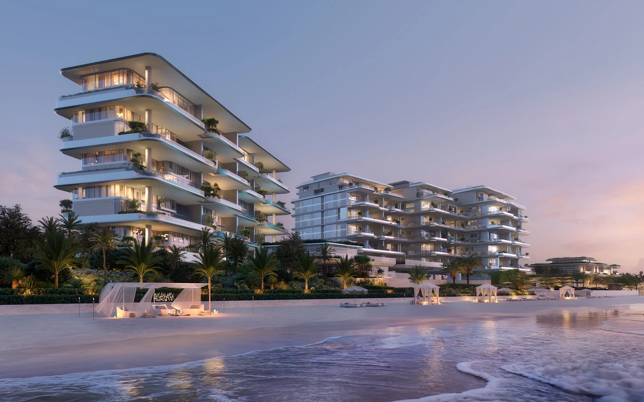 ORLA and ORLA Infinity Dorchester Collection by Omniyat illuminated beachfront residences with curved terraces palm landscaping and private beach cabanas at dusk in Dubai - Presented by Tohid Fetrat