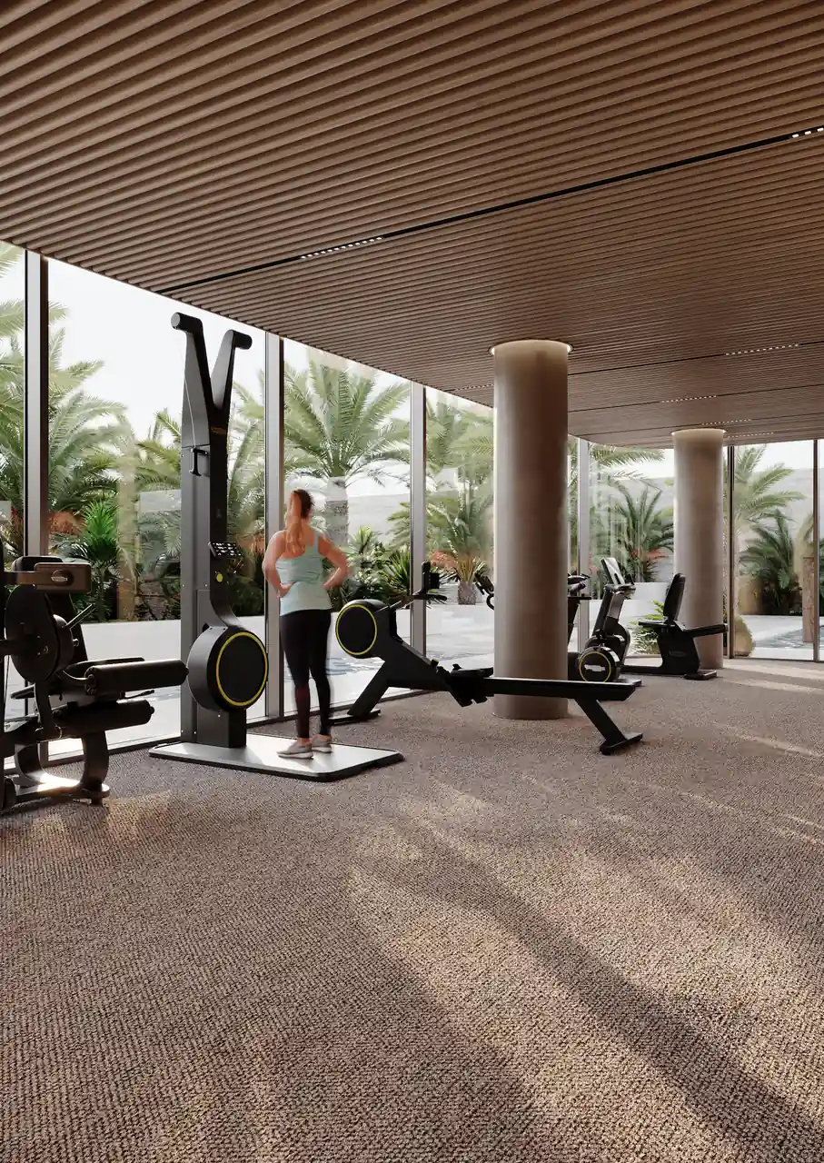 ORLA Infinity Dorchester Collection by Omniyat fitness center with cardio equipment rowing machines travertine columns and floor to ceiling glazing onto a palm garden in Dubai - Presented by Tohid Fetrat