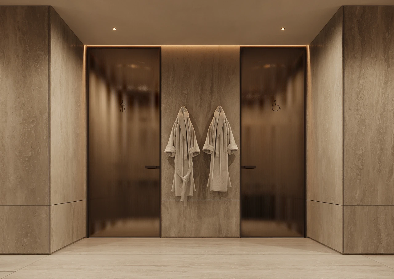 ORLA Infinity Dorchester Collection by Omniyat spa and gym shower suites with fluted bronze glass doors travertine walls concealed lighting and hanging robes in Dubai - Presented by Tohid Fetrat