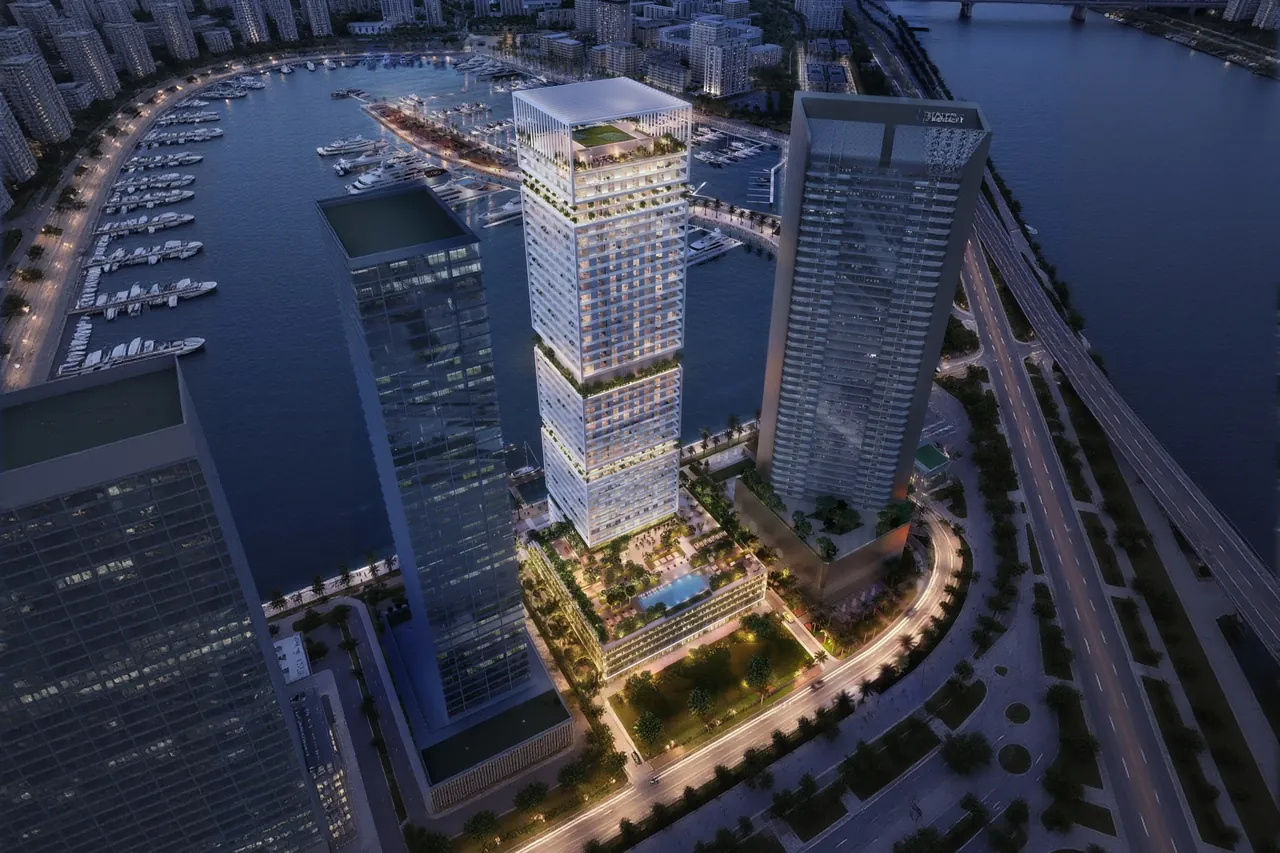 Saria by Beyond in Dubai Maritime City aerial night view of the illuminated tower above its podium with the yacht marina and coastal highway in Dubai - Presented by Tohid Fetrat