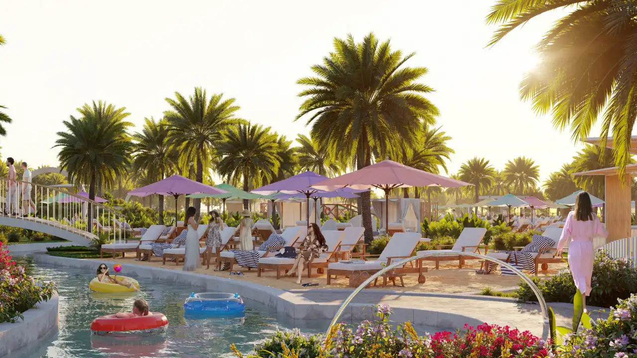 The Farmhouses at DAMAC Hills 2 by DAMAC community lagoon beach club with sun loungers, shaded cabanas, palm trees and waterfront relaxation areas in Dubai Presented by Tohid Fetrat