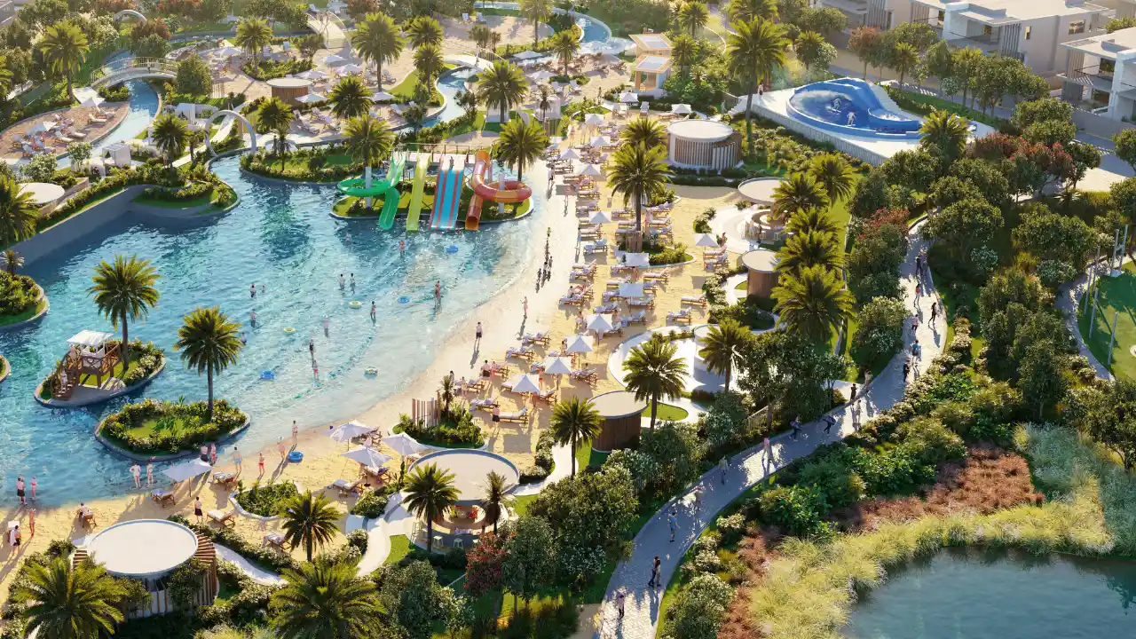 The Farmhouses at DAMAC Hills 2 by DAMAC aerial view of the community lagoon with a sandy beach, water slides, resort style pools, landscaped gardens and leisure amenities in Dubai Presented by Tohid Fetrat