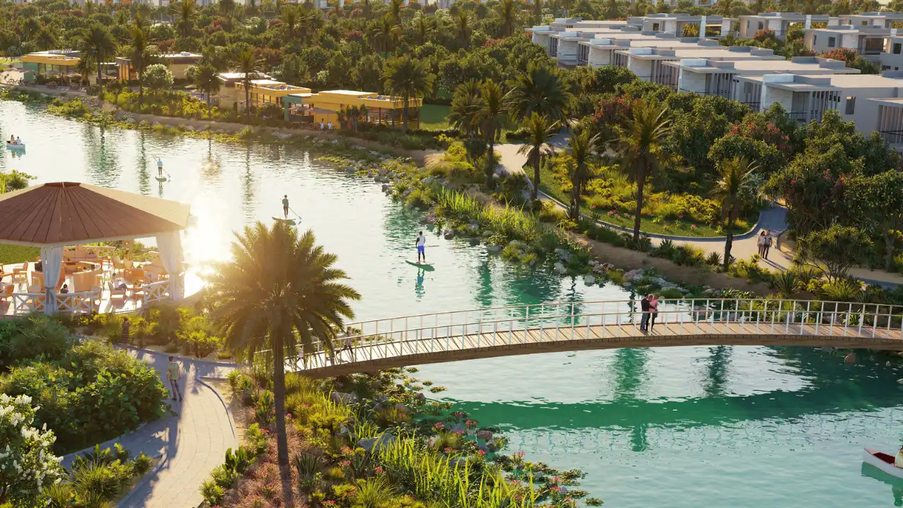 The Farmhouses at DAMAC Hills 2 by DAMAC aerial view of the community lake with a pedestrian bridge, waterfront pavilion, landscaped gardens and leisure activities in Dubai Presented by Tohid Fetrat